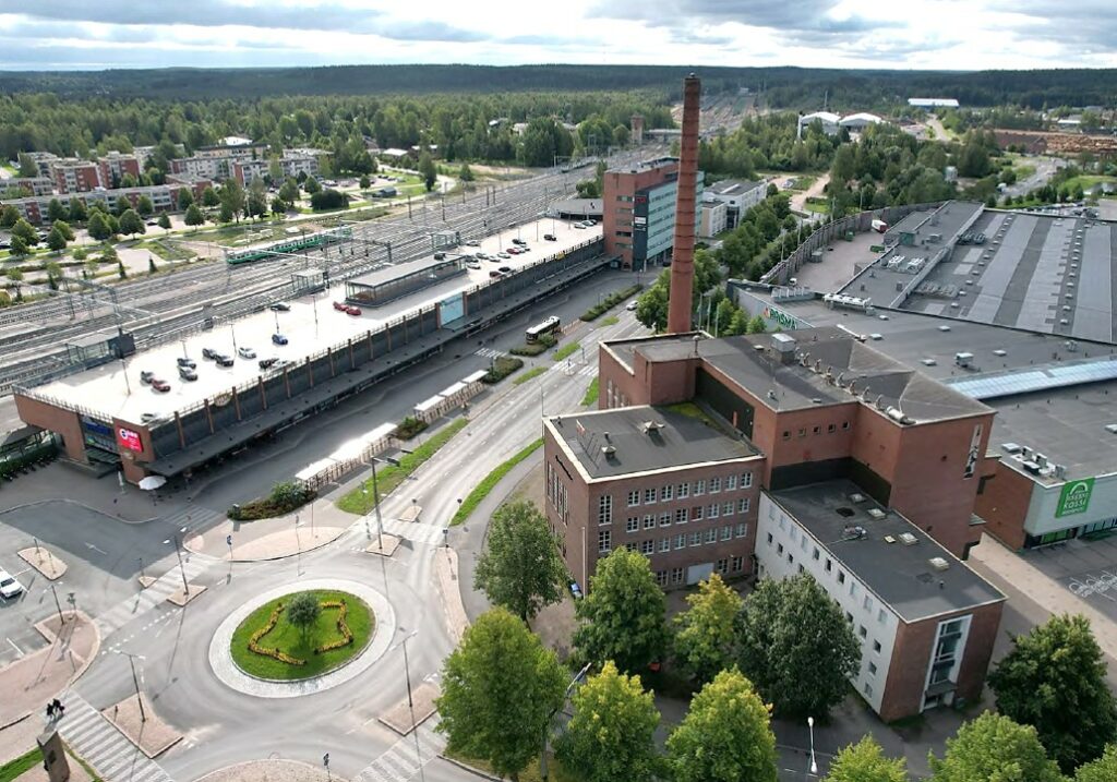 Yläkulmasta otettu kuva, jossa näkyy etualalla Voimalan punatiilinen rakennus ja taustalla Matkakeskus, Prisma ja laajemmin asutusta.